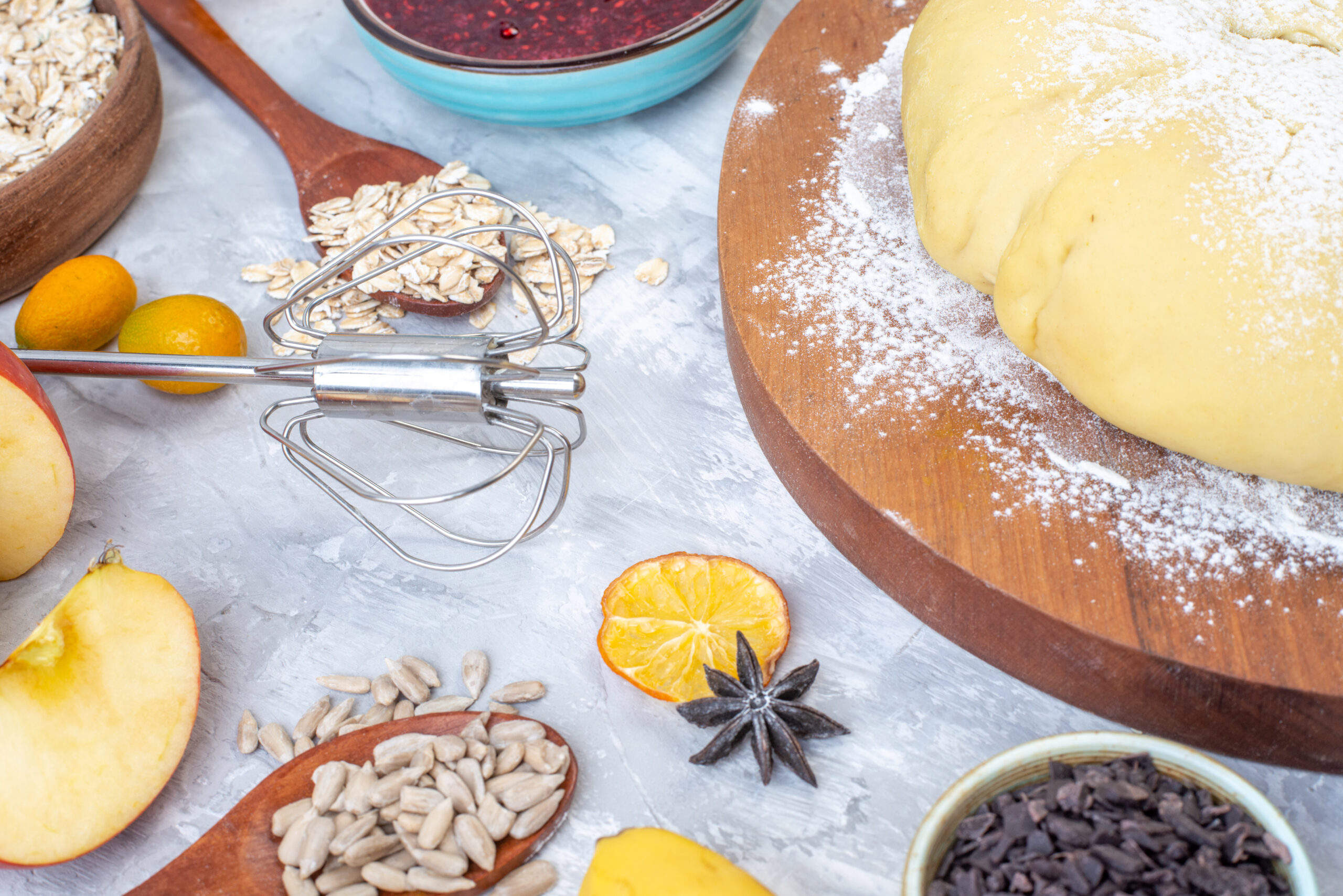 front-view-raw-pastry-flour-round-wooden-board-grater-hazelnuts-fresh-fruits-chocolates-gray-background